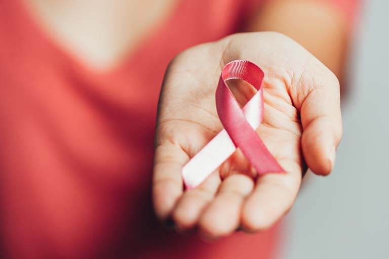 close up of a hand holding cancer pink ribbon 