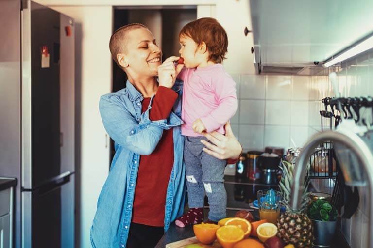 after chemo, a bald woman feeding her kid